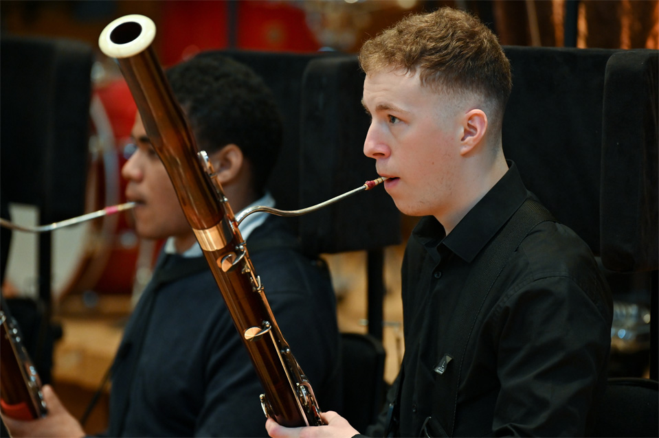 A male bassoon player performing in an orchestrea.